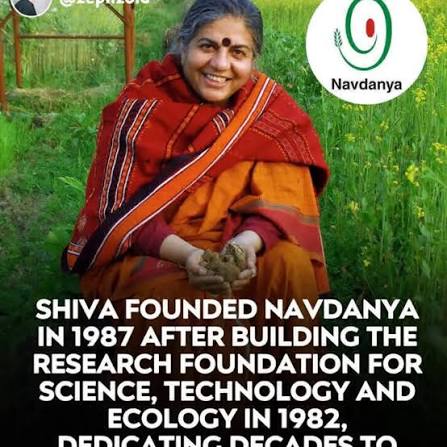 Vandana Shiva sonríe sentada en un campo verde mientras sostiene tierra o semillas en las manos. La imagen incluye el logotipo de Navdanya y texto en inglés sobre la fundación de esta organización, dedicada a la biodiversidad y la defensa de las semillas campesinas